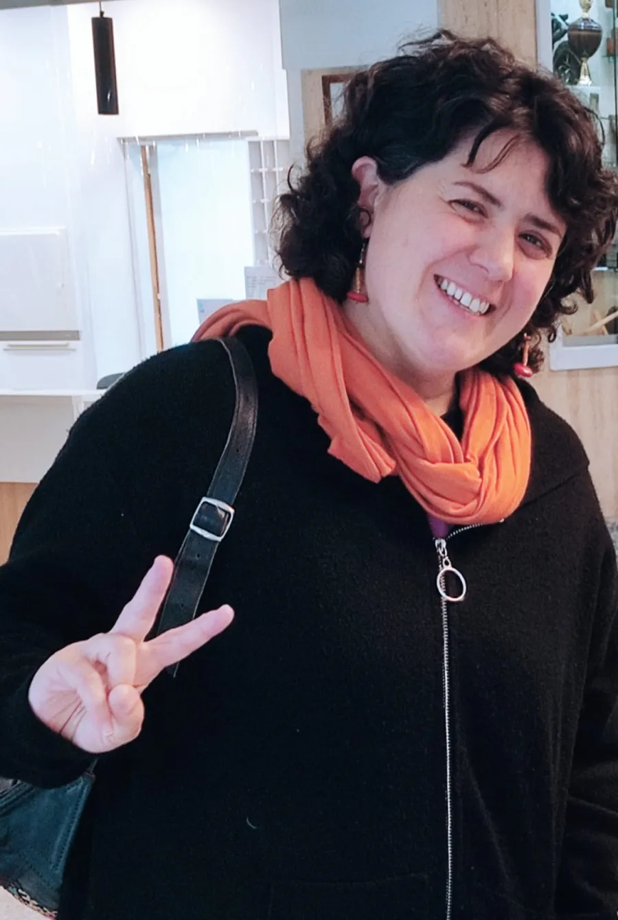 Almudena Ovejero, sonriente, con una bufanda naranja en la entrada del centro